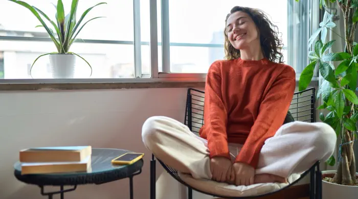 Emotional freedom and clarity — the benefits of releasing fear, doubt, and inner resistance through deep healing Smiling woman in orange sweater relaxing indoors — feeling emotionally lighter, confident, and aligned after healing inner blocks